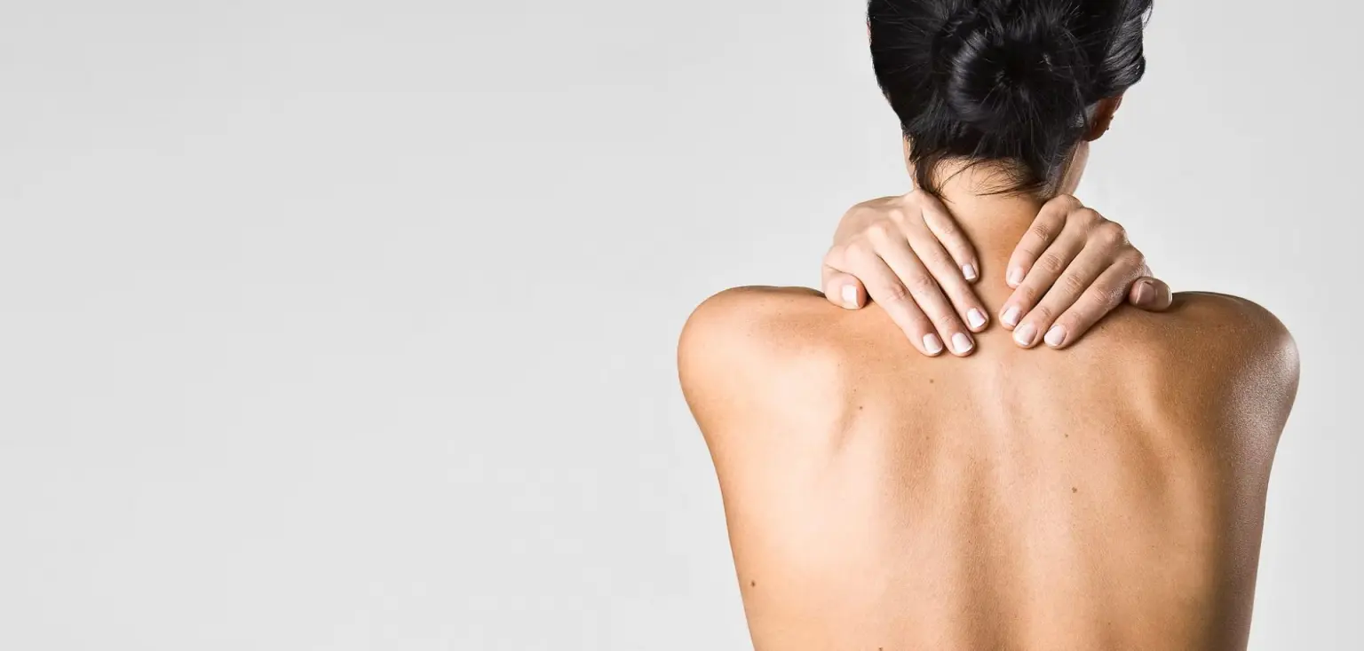 Femme tenant sa nuque douloureuse à cause de tensions cervicales liées au travail sur écran